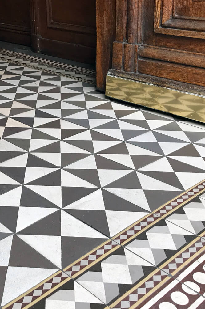 Alte, historische Fliesen in Hausflur und Eingangbereich restauriert mit Schachbrett-Muster und intarsiertem Ornament- und Mosaik-Rand. Epoche: Gründerzeit und Jugendstil